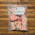 A clear plastic bag of beef bones, displayed on a rustic wooden board