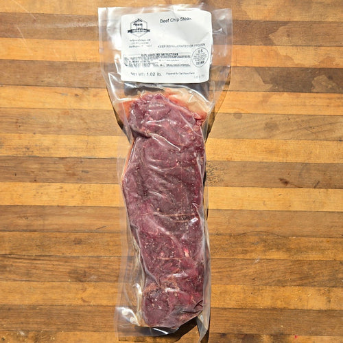 A vacuum-sealed Beef Chip Steak package placed on a wooden cutting board.