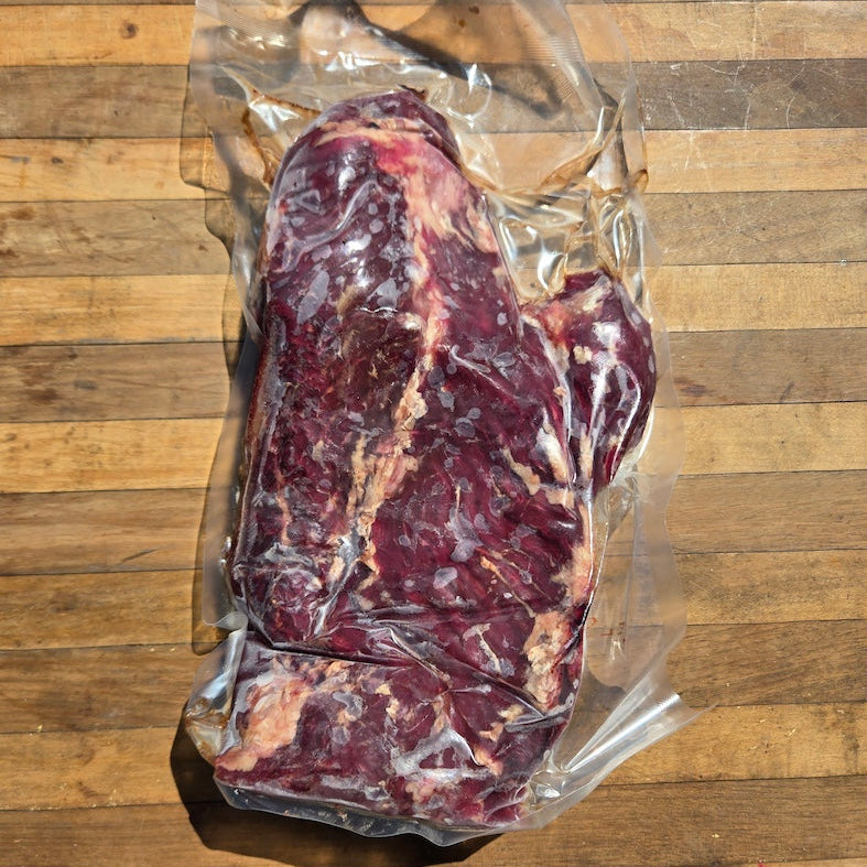  A vacuum-sealed package of beef hanger steak on a wooden surface
