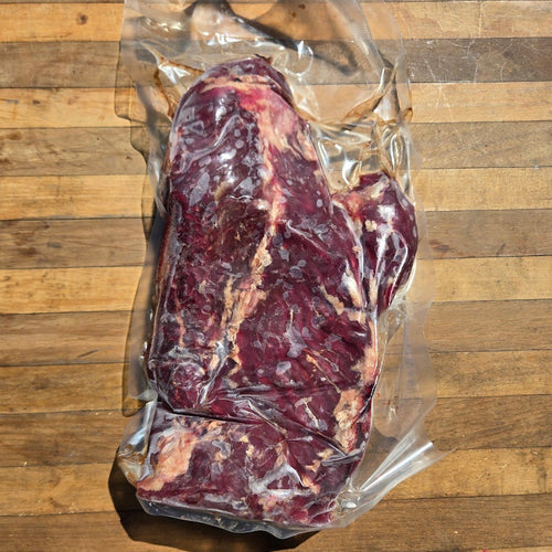  A vacuum-sealed package of beef hanger steak on a wooden surface