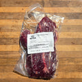 A vacuum-sealed package of beef hanger steak on a wooden surface, with a white label showing the product name and weight.