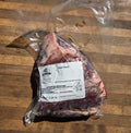 A vacuum-sealed package of beef heart on a wooden surface