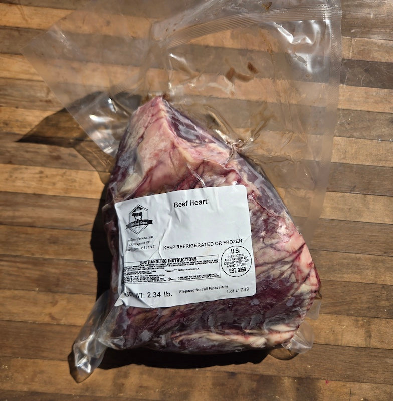 A vacuum-sealed package of beef heart on a wooden surface