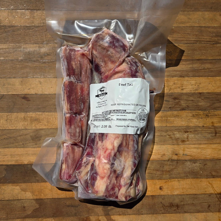 A vacuum-sealed package of raw beef bones, displayed on a wooden surface