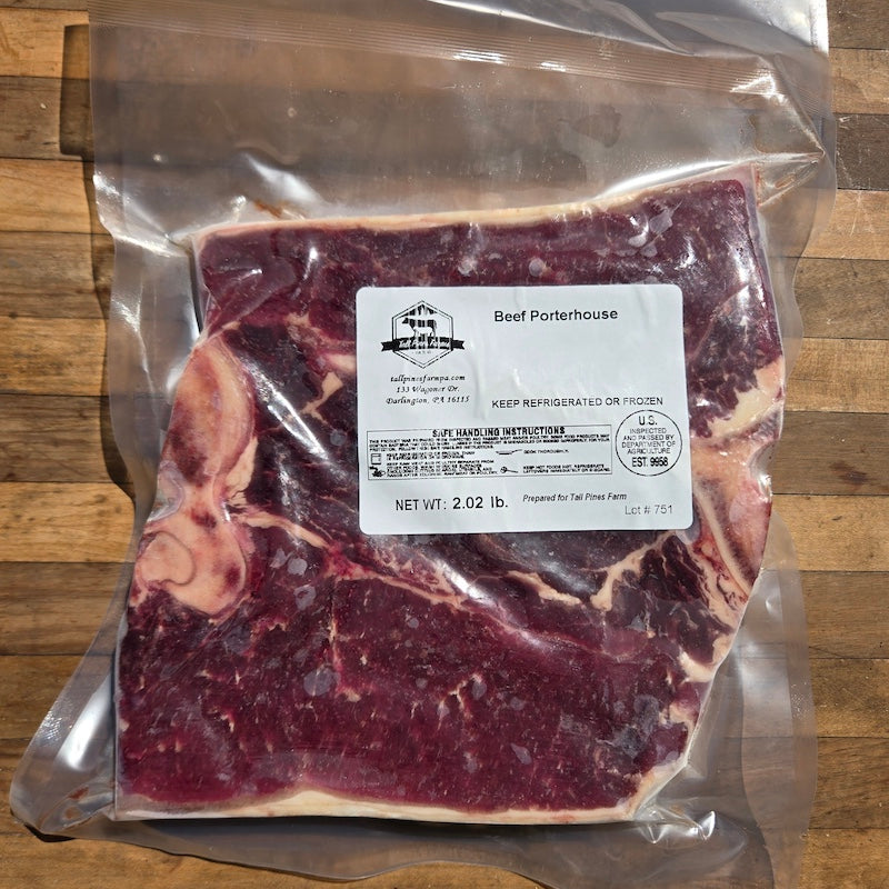 A vacuum-sealed package of frozen Beef Porterhouse, displayed on a rustic wooden surface