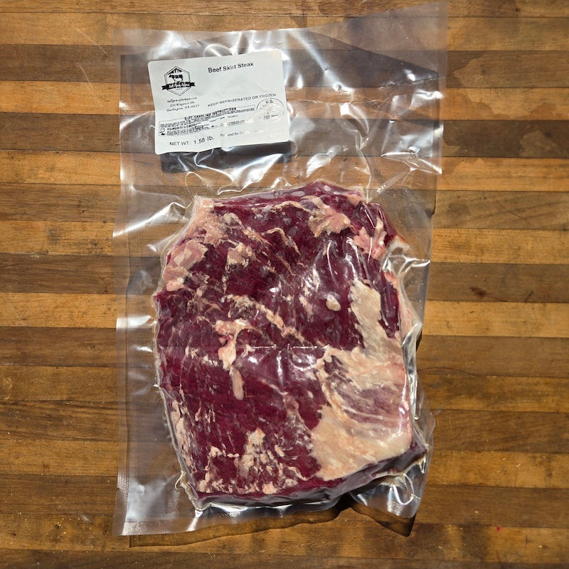 a vacuum-selaed package of beef skirt steak, displayed on a rustic wooden board