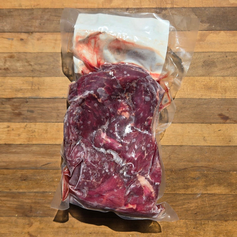 A vacuum-sealed package of beef stew meat with a white label reading 'Beef Stew Meat' placed on a wooden surface.