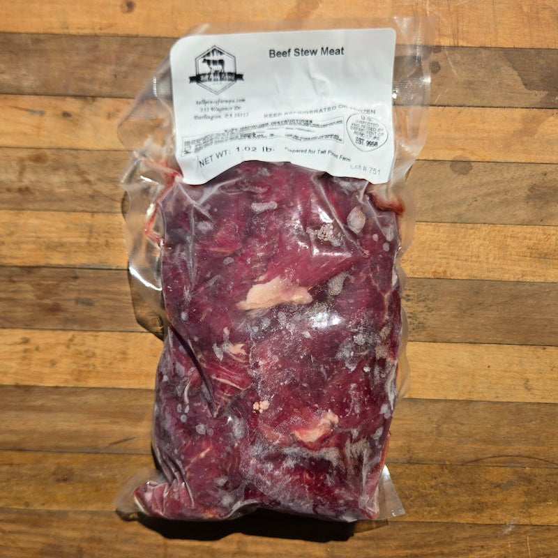 A vacuum-sealed package of beef stew meat with a white label reading 'Beef Stew Meat' placed on a wooden surface.