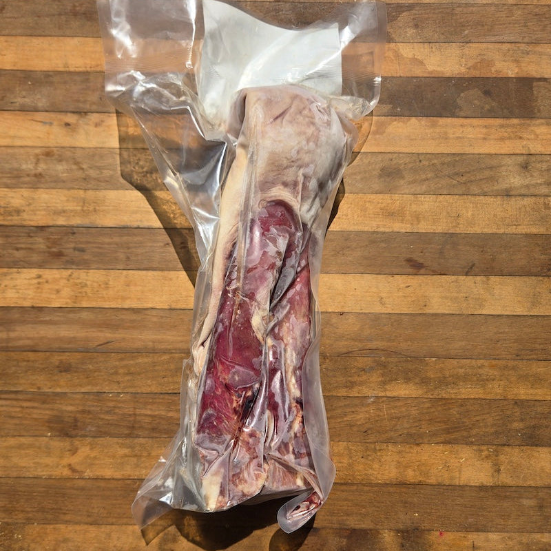a vacuum-sealed package of beef tongue, displayed on a wooden surface