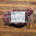A vacuum-sealed package of beef top round roast with a white label reading 'Beef Top Round Roast' placed on a wooden surface.