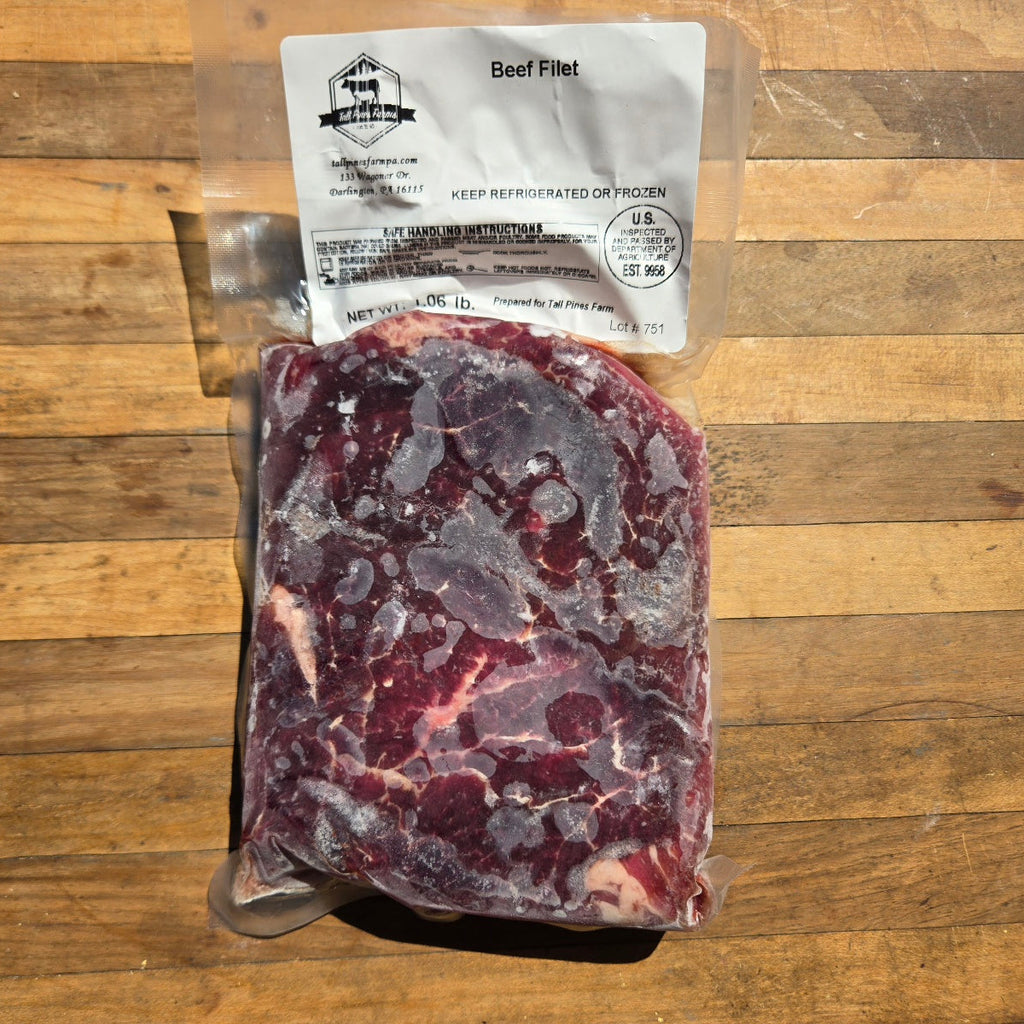 A vacuum-sealed package of beef fillet meat with a white label on a wooden surface. 